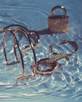 金手镯耳环环Jewelery蓝色的水背景奢侈品魅力假期美设计<strong>珠宝品牌</strong>广告