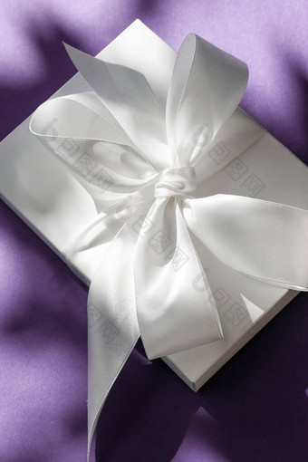奢侈品假期白色礼物盒子丝绸丝带弓紫罗兰色的背景奢侈品婚礼生日现在