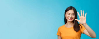 特写镜头好看的友好的快乐的亚洲女人提高棕榈显示数量微笑快乐描述的事情站蓝色的背景乐观的沟通