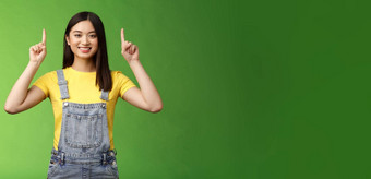 友好的可爱的好看的亚洲浅黑肤色的女人女指出提高手指前广告自信的显示促销微笑满意介绍产品绿色背景