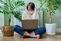 女人温暖的毛衣移动PC坐着加热散热器首页