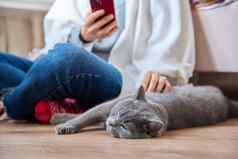 女坐着地板上智能手机宠物猫睡觉老板