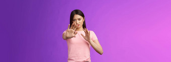 不高兴强烈的不情愿的亚洲女孩阻塞保护脸提高手停止禁止手势皱着眉头生闷气的拒绝困扰提供站紫色的背景拒绝
