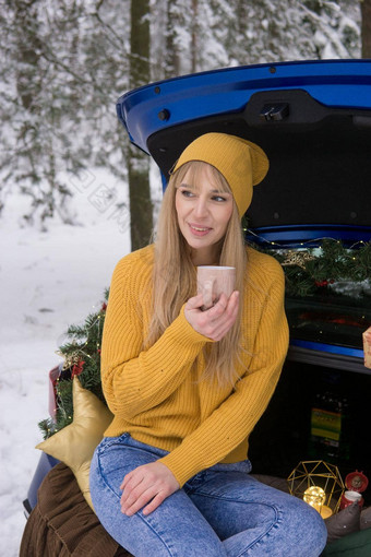 女人冬天白雪覆盖的森林树干蓝色的车装饰圣诞节装饰概念圣诞节冬天假期