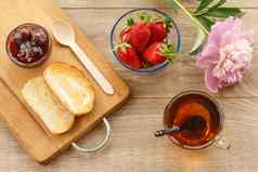 杯茶自制的草莓小时碗新鲜的浆果烤面包木背景