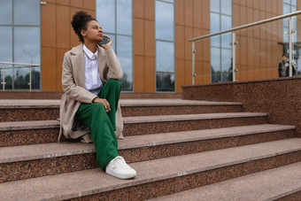 年轻的美国女自由市场营销人员会说话的电话坐着步骤办公室建筑