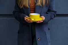 年轻的美丽的金发女郎女人灰色的外套饮料热茶黄色的杯冷秋天一天美味的温暖的喝阳台咖啡馆