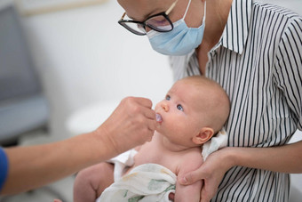儿科医生管理口服疫苗接种轮状病毒感染婴儿存在妈妈。孩子们健康护理疾病预防