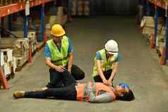 仓库工人说谎无意识的混凝土地板上的同事们帮助给受伤的援助