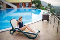 美丽的年轻的女人泳衣白色衬衫坐在太阳懒人池按摩身体防晒霜夏天皮肤护理保护皮肤燃烧