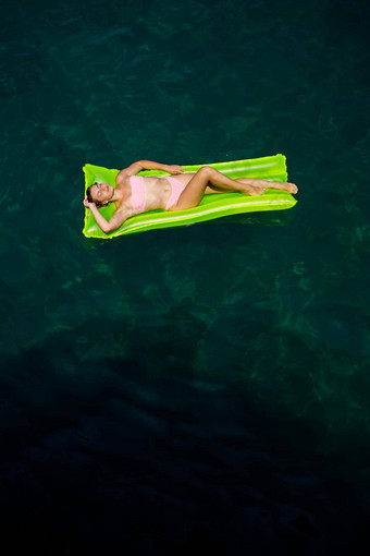 年轻的女人泳衣游泳充气明亮的床垫海夏天假期概念