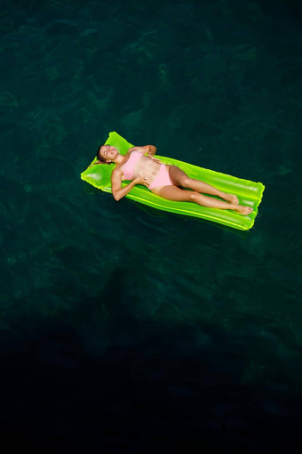 年轻的女人泳衣游泳充气明亮的床垫海夏天假期概念