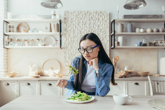 年轻的亚洲女人不开心饮食厨房女人吃健康的食物吃沙拉健康的食物少年首页