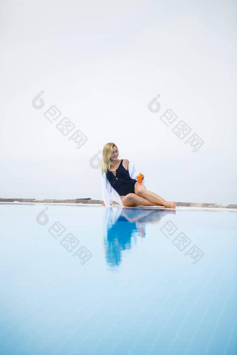 年轻的美丽的女人泳衣坐在池涂片皮肤防晒霜护肤品夏天