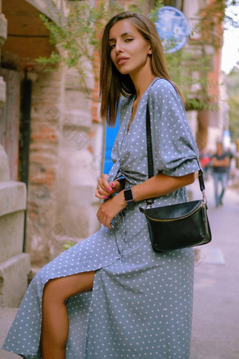 金发女郎女孩长蓝色的衣服小黑色的手提包肩膀走城市时尚风格特写镜头拍摄
