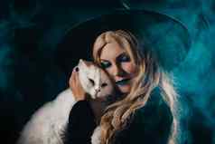漂亮的女巫白色毛茸茸的魔法猫黑暗背景快乐万圣节化妆舞会服装技巧治疗经典巫婆