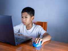 关闭男孩坐在盯着移动PC手持有鼠标教育概念教育信息搜索复制空间