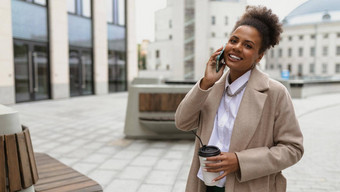 非洲美国女商人会说话的移动电话宽微笑杯咖啡手移动互联网银行概念