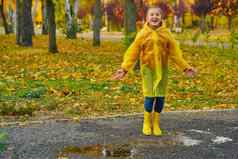 快乐女孩黄色的雨衣橡胶靴子秋天走