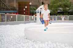 快乐女孩玩白色塑料球池娱乐公园操场上孩子们