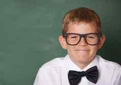 聪明的男孩快乐年轻的小学生蝴蝶结微笑相机前面黑板上Copyspace