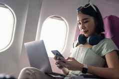 有吸引力的亚洲女人乘客飞机读新闻网络智能手机无线网络董事会旅游旅行者概念