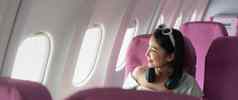快乐年轻的亚洲女人乘客座位窗口飞机旅行概念