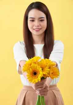 快乐年轻的女人持有花束花手黄色的背景