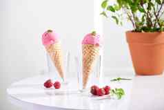 华夫格锥填满新鲜的树莓冰奶油玻璃杯新鲜的树莓坐着桌面
