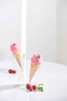 华夫格锥填满新鲜的树莓冰奶油玻璃杯新鲜的树莓坐着桌面