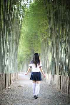 肖像美丽的亚洲日本高学校女孩统一的竹子森林背景