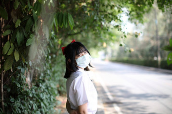 亚洲学校女孩面具城市城市树背景