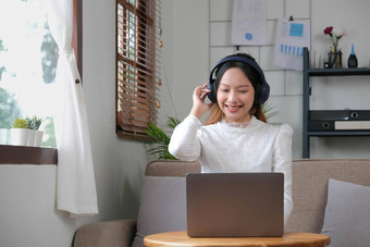 年轻的成人快乐微笑拉美裔亚洲学生穿耳机会说话的在线闲谈，聊天会议移动PC大学校园虚拟办公室大学女学生学习远程