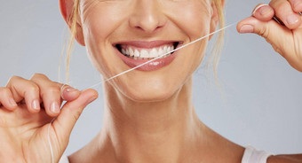 牙齿用牙线清洁牙齿牙科健康女人微笑清洁口灰色模型工作室背景手模型字符串护理牙健康口服医疗保健微笑