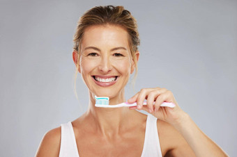 牙齿牙科口服卫生女人刷牙牙刷牙膏工作室灰色的背景健康医疗保健脸女采取护理口牙龈