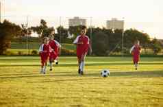 体育健身足球培训女孩团队玩草场团队合作足球游戏健康锻炼孩子们学习玩有竞争力的匹配能源足球球