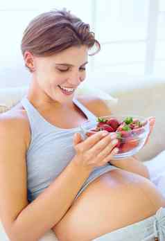 美味的营养物质婴儿快乐年轻的怀孕了女人持有碗完整的草莓