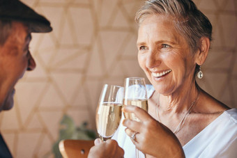 高级夫妇香槟饮料烤面包房子首页婚姻周年纪念日庆祝活动事件退休成功快乐微笑爱上了年纪的男人。女人享受酒精玻璃