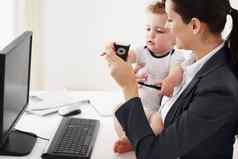 采取时间债券工作工作妈妈。坐着前面移动PC显示手机婴儿