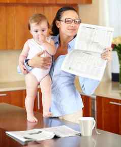采取时间抓新闻stressed-looking单妈妈持有婴儿读纸