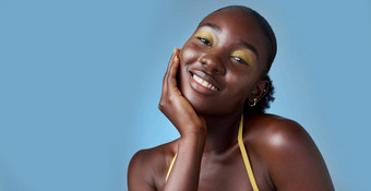 黑色的女人微笑化妆模型护肤品美化妆品蓝色的背景模型快乐手脸皮肤健康健康肖像工作室背景