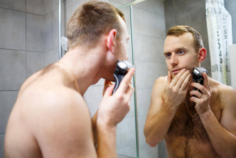 男人。刮胡子脸电<strong>剃须刀</strong>前面镜子皮肤刺激浴过程
