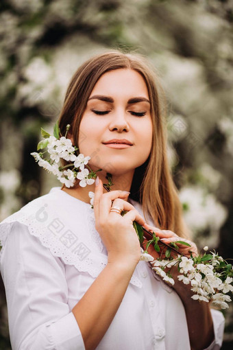 肖像金发的年轻的女人白雪公主衣服站开花苹果树女孩走盛开的苹果果园春天