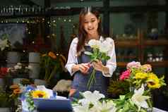 快乐年轻的女人小业务老板使美丽的花束花花商店