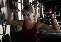 健身女人工作健身房锻炼肱二头肌运动女孩培训美丽的健身女人提升哑铃健身运动女人显示训练有素的身体