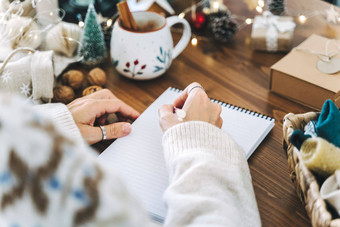 女人手持有笔记事本首页冬天假期圣诞节目标计划使列表一年圣诞节概念女孩写作笔记本圣诞节装饰礼物盒子