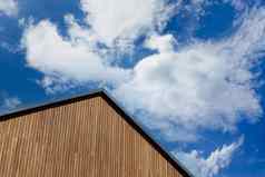 木板材三角墙的屋顶现代房子蓝色的天空风景如画的云