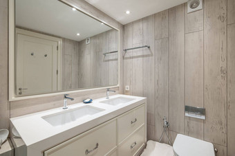 美丽的浴室舒缓的柔和的颜色大镜子反映了通过浴房间明亮灯建光滑的拉伸天花板汇建大理石工作台面
