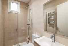 明亮的浴室米色颜色光滑的陶瓷瓷砖墙照明浴室淋浴玻璃栏杆大镜子水槽散热器干燥毛巾