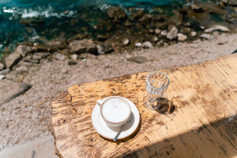 卡布奇诺咖啡拿铁咖啡杯杯子玻璃水站木表格咖啡馆风景海山背景复制空白空间